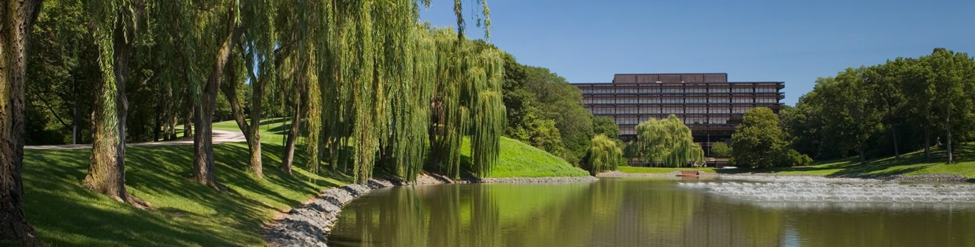 Front view of the John Deere headquarters building with pond and willow trees in the foreground