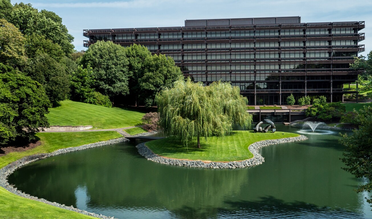 Aerial front view of the John Deere headquarter building with the pond and trees in the foreground