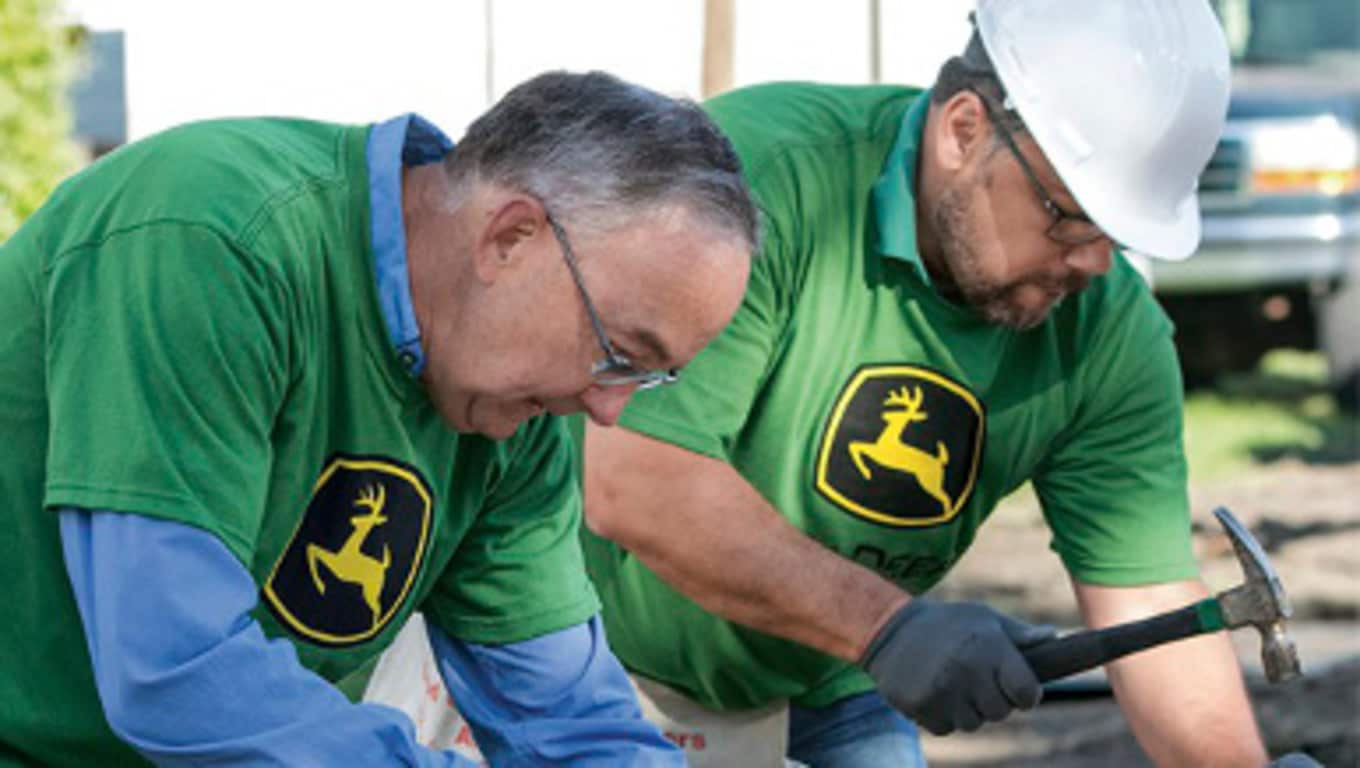 John Deere CEO Sam Allen and another Deere employee working at a volunteer event