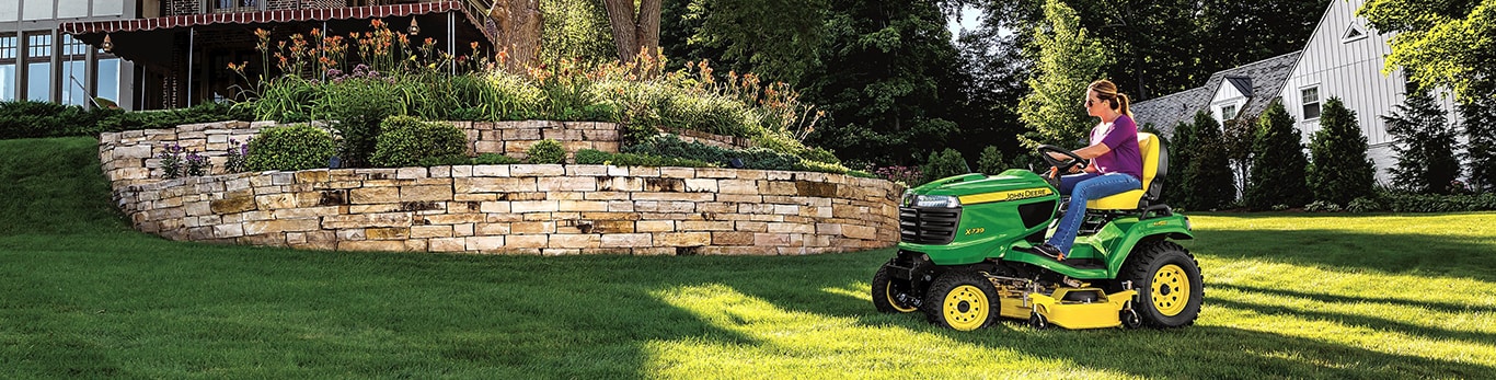 woman mows lawn on a John Deere riding mower