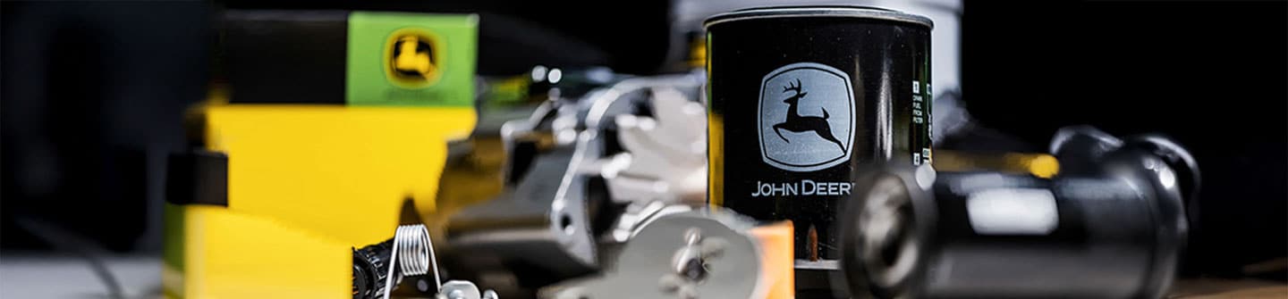 Close-up of John Deere parts, black oil filter, surrounded by various machinery components.