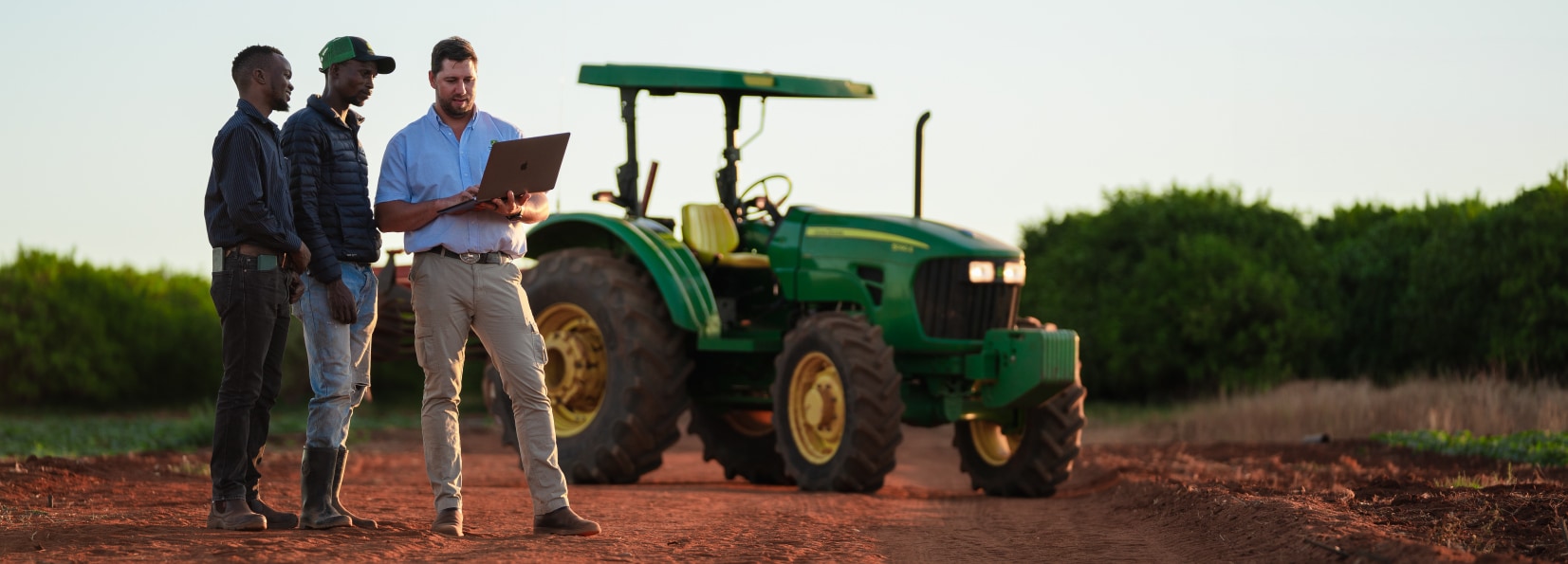 Few people standing and discussing besides John Deere tractor