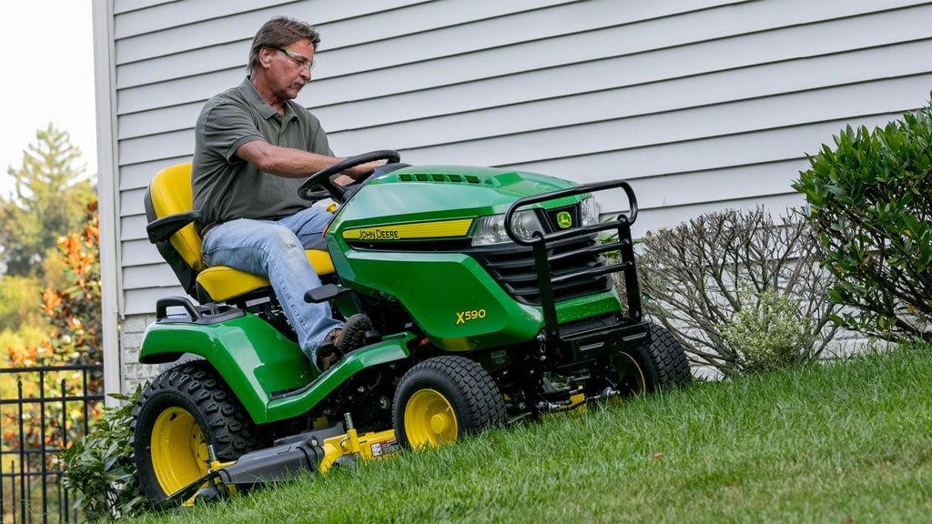 man mowing lawn by side of a house