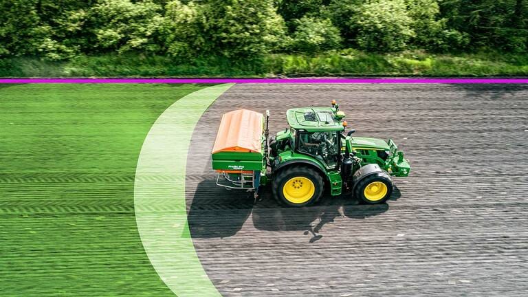 Side right view of John Deere tractor driving on dirt field